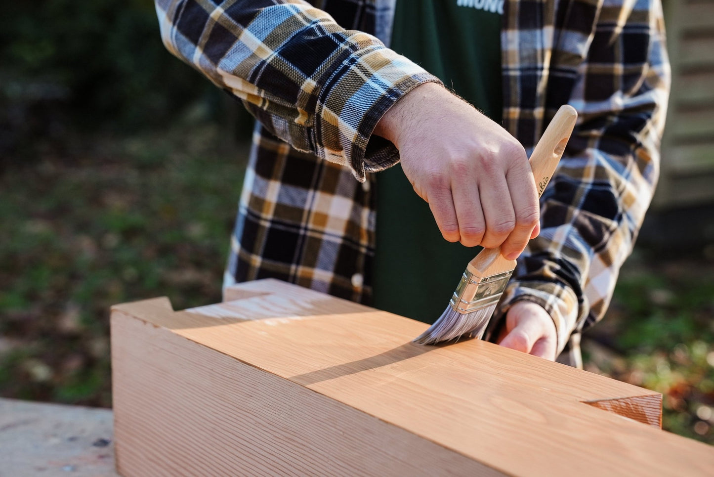Person applying Rubio Monocoat oil on a wooden surface outdoor.